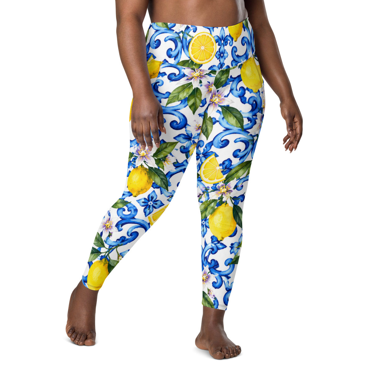 A person modeling high-waisted leggings with a white base and a colorful print of blue scrollwork, yellow lemons, and green leaves, shown against a plain white background.