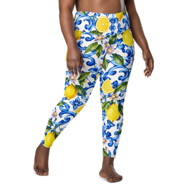 A person modeling high-waisted leggings with a white base and a colorful print of blue scrollwork, yellow lemons, and green leaves, shown against a plain white background.