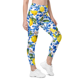 A model wearing high-waisted leggings with a vibrant blue, yellow, and green floral and lemon pattern on a white background, paired with white sneakers.