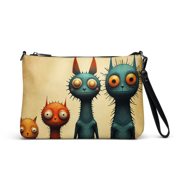 A zip-around crossbody bag with a black wrist strap and shoulder strap, featuring a printed design of four cartoon cats in shades of teal, orange, and beige on a cream background.