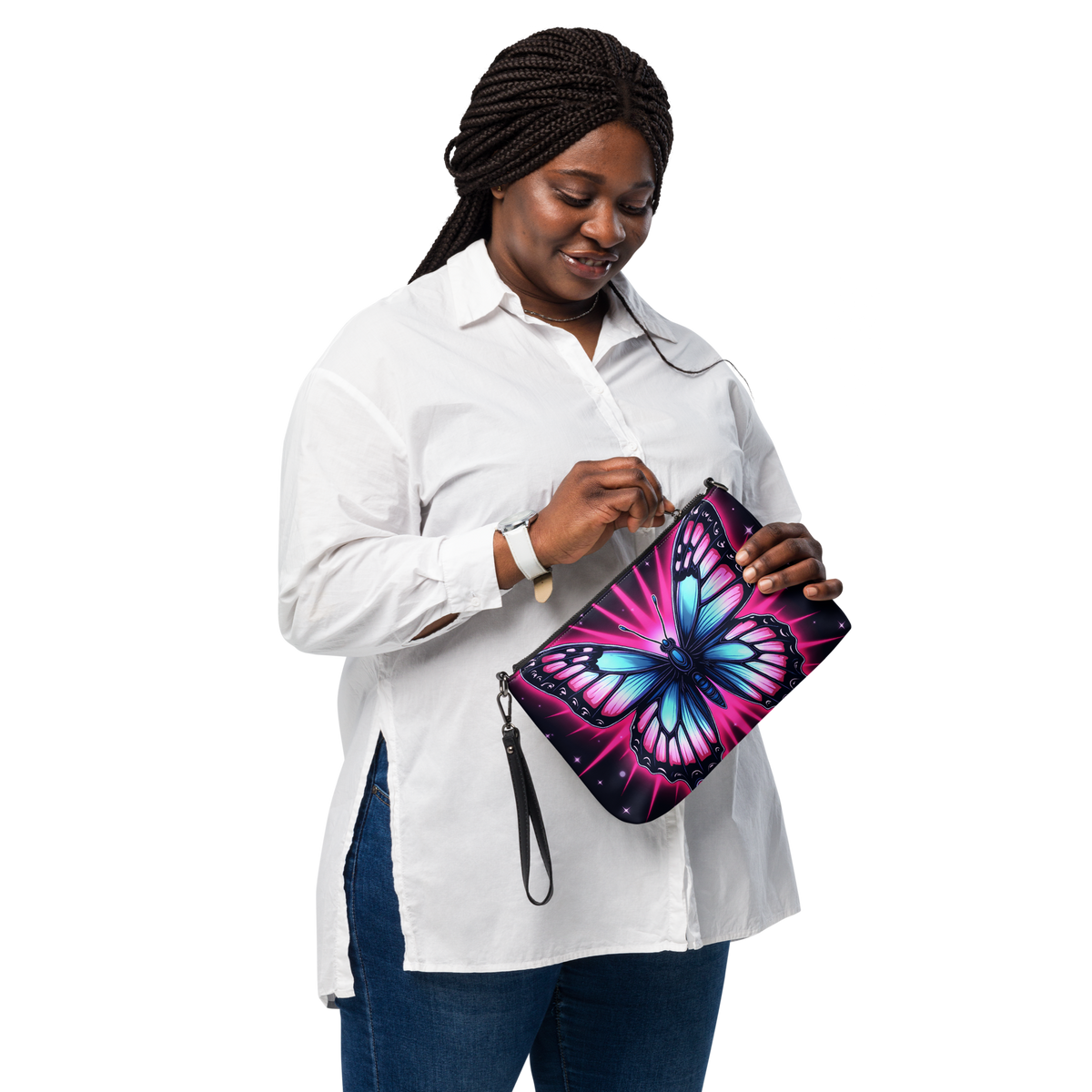 A woman wearing a white button-down shirt and blue jeans holds a black crossbody  bag decorated with a vibrant, colorful butterfly design in pink, blue, and purple, against a solid white background.