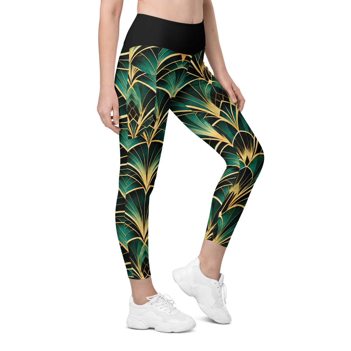 A person modeling high-waisted leggings with a bold green and gold palm leaf pattern, paired with white sneakers, on a plain white background.