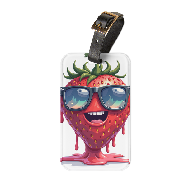 A clear rectangular luggage tag with a black strap and gold buckle, featuring a cartoon strawberry character wearing dark sunglasses and dripping pink liquid, shown on a plain white background.