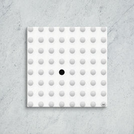 Square tile with a pattern of gray dots and one black dot on a concrete surface