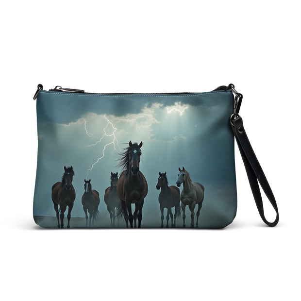 A zippered wristlet clutch with a printed design of a herd of horses under a stormy sky with lightning, shown on a plain white background.