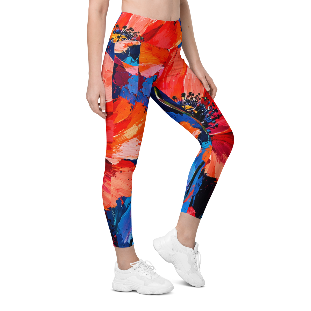 A model wearing high-waisted leggings with a vibrant abstract paint-splatter pattern in red, orange, blue, and black, paired with white sneakers against a plain white background.